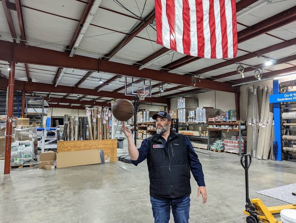 Brad Bounds spinning a basketball on his finger inside the Bounds Flooring warehouse.